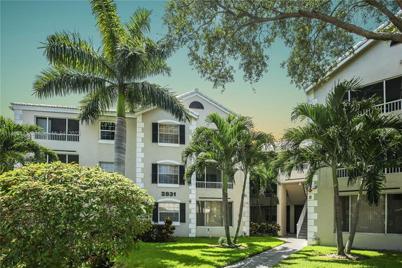 Front view of a three-story residential building with palm trees.