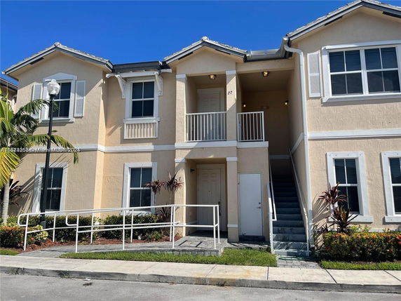 Front view of a two-story residential building with stairs leading to an upper level entrance.