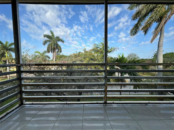 A balcony view showing palm trees and a street beyond a railing.