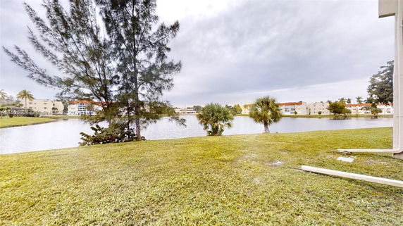 View of a lake with buildings in the background and trees surrounding the area.