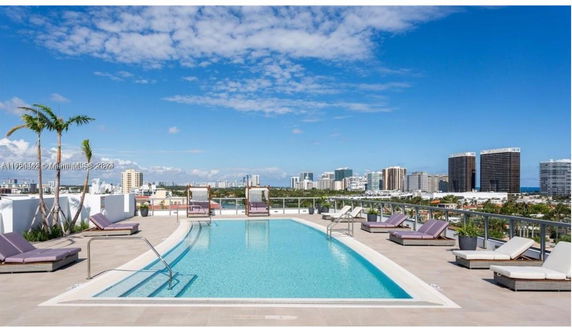 Rooftop swimming pool with lounge chairs and city skyline view.