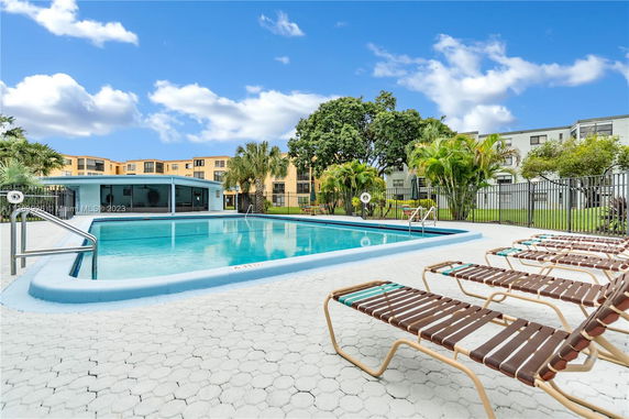 Outdoor swimming pool with lounge chairs and surrounding trees.