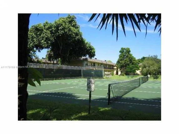 Tennis court surrounded by trees and buildings.