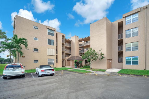Front view of a multi-story apartment building with parking area.
