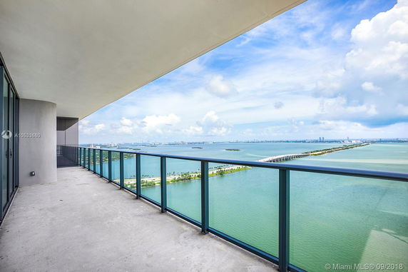 Panoramic view from a high-rise balcony overlooking a body of water with a distant city skyline.