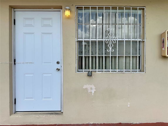 Front view of a building facade with a white door and barred window.