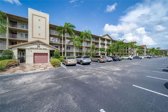 Front view of a multi-story residential building with parking area.