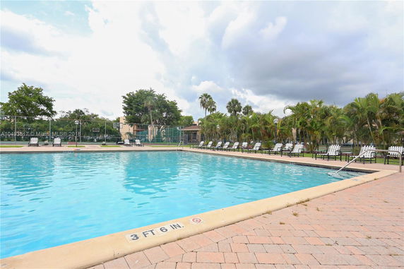 Outdoor swimming pool with seating area and surrounding greenery.