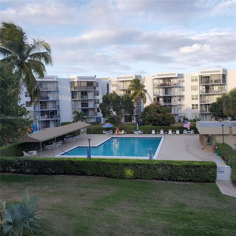 View of a swimming pool area with multiple residential buildings in the background.