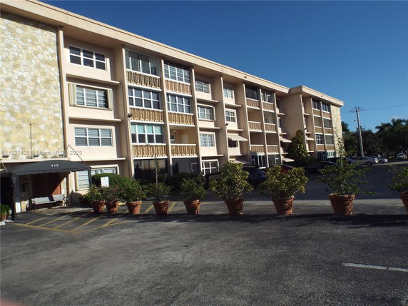 Front view of a multi-story residential building with balconies and a stone facade entrance.