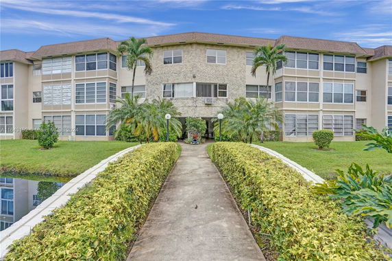 Front view of a three-story residential building with symmetrical design and landscaped surroundings.