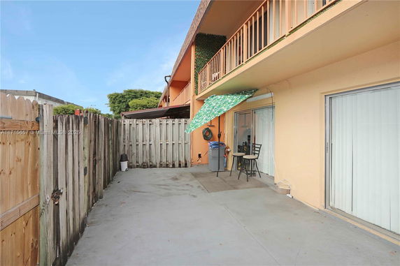 Exterior view of a fenced patio area with sliding doors and an awning.