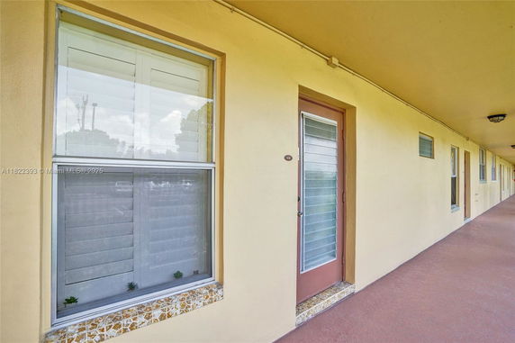 Exterior view of a building corridor with doors and windows.