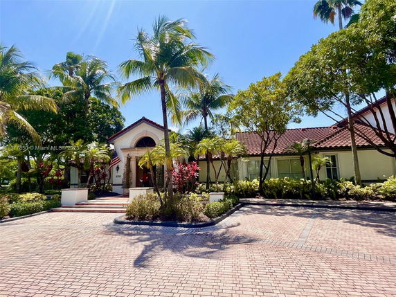 Front view of a single-story house with red-tiled roof and palm trees.