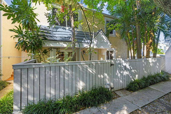 Front view of a two-story house with a fenced yard and trees.
