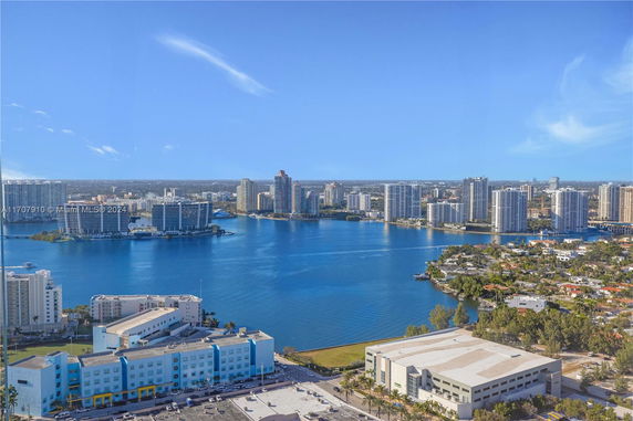Panoramic view of a city skyline with high-rise buildings and a large body of water in the foreground.