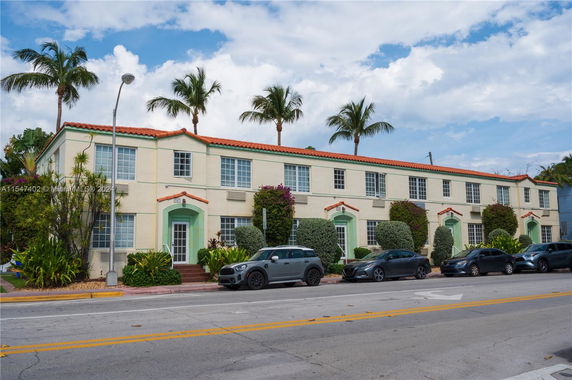 Front view of a two-story building with multiple entrances and palm trees in the background.