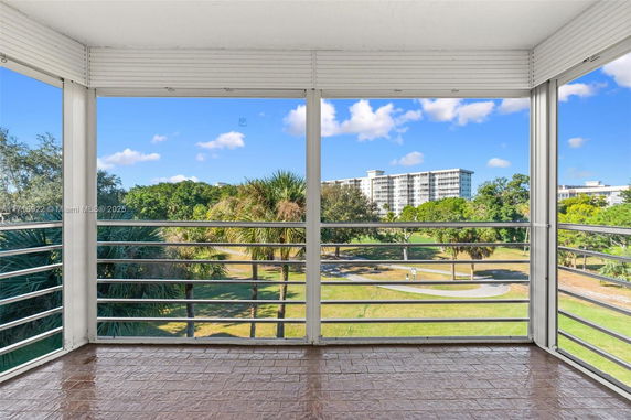 View from a balcony showing a landscape with trees and a distant building.