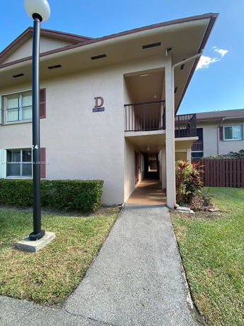 Front view of a two-story apartment building with a walkway leading to the entrance.