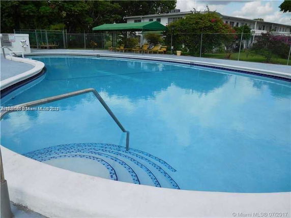 Outdoor swimming pool with steps and a metal handrail.