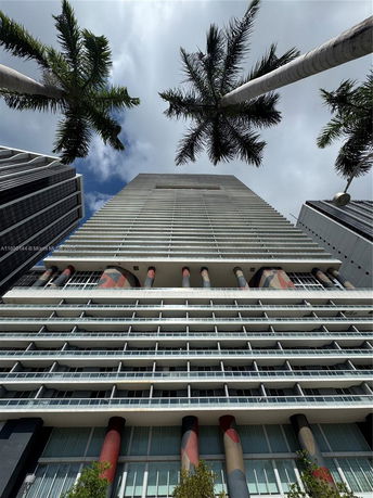 Looking up at a tall modern building with balconies and colorful columns.