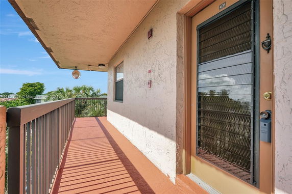 Exterior walkway with railing and door leading to an apartment or unit entrance.