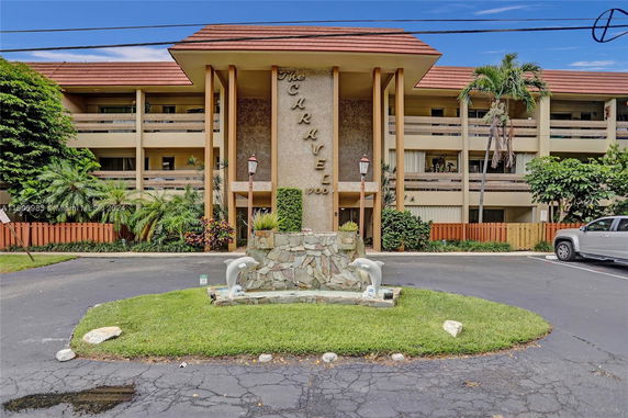 Front view of a multi-story building with a prominent sign and landscaped entrance.