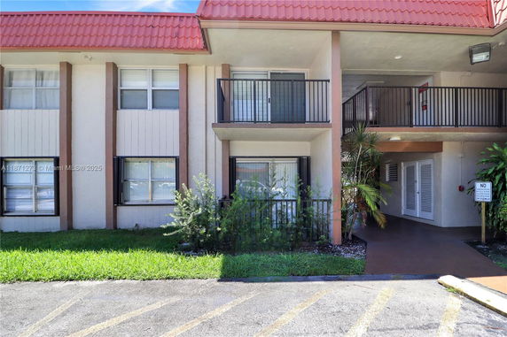 Front view of a two-story building with red roof tiles and a small balcony.