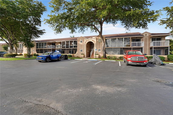 Outdoor parking area in front of a two-story building with parked vehicles.