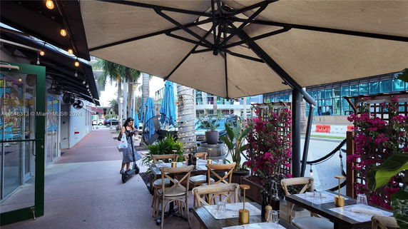 Outdoor dining area of a restaurant with tables and chairs under large umbrellas.