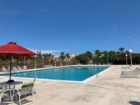 Outdoor swimming pool with deck chairs and a parasol.