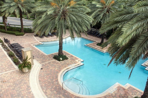 Outdoor swimming pool area with palm trees and lounge chairs.