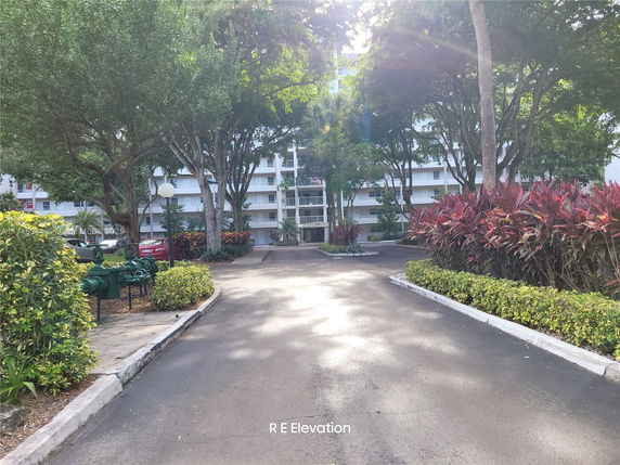 Front view of a multi-story residential building with surrounding greenery.