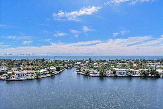 Panoramic view of a coastal residential area with waterfront homes and ocean in the background.