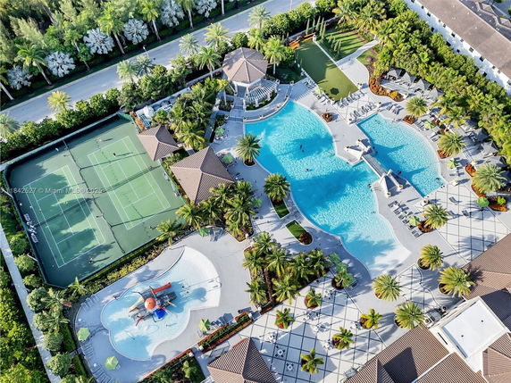 Aerial view of a recreational complex with swimming pools, tennis courts, and play area.