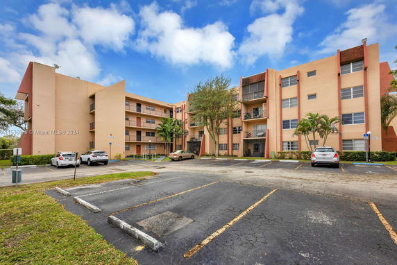 Exterior view of a multi-story building with parking spaces in front.