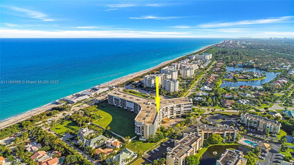 Aerial view of coastal residential buildings with a wide ocean backdrop.