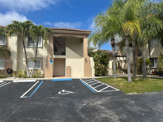 Front view of a two-story building with palm trees and a handicap parking space.