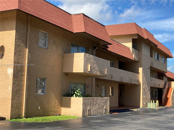 Front view of a multi-story building with balconies and red roofing.
