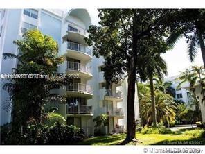 Front view of a multi-story residential building with balconies and surrounded by trees.