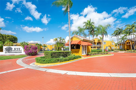 Front view of a residential complex with yellow buildings and landscaped drive.