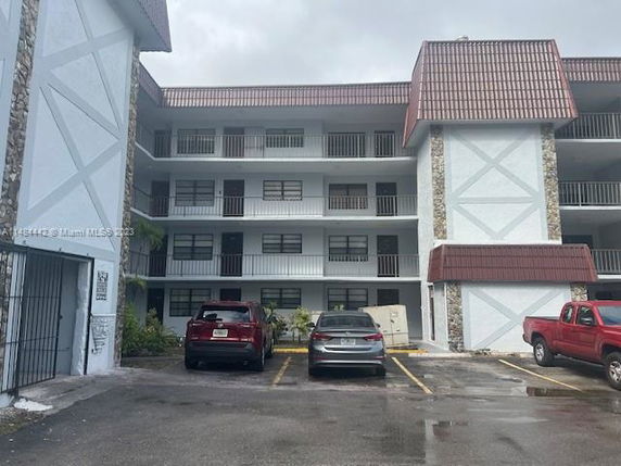 Front view of a multi-story residential building with parking area.