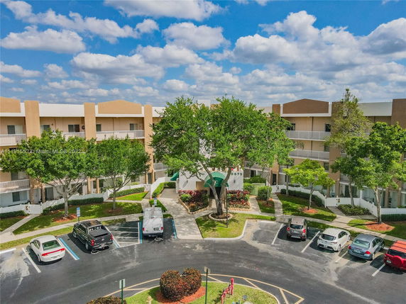 Parking area in front of a multi-story residential building with balconies.