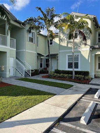 Front view of a multi-story building with a staircase and palm trees.