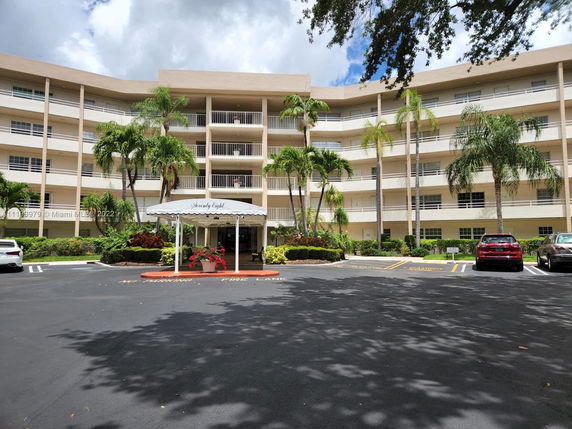 Front view of a multi-story residential building with balconies and a covered entrance.
