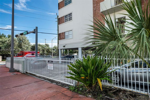 Outdoor parking area with a gated entrance next to a multi-story building.