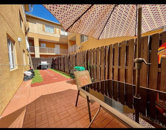 Outdoor patio area with a table, umbrella, and view of adjacent buildings.