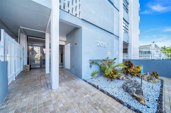 Front view of a multi-story building entrance with a stone garden.