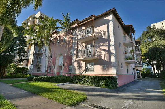Front view of a multi-story building with balconies and a pink facade.