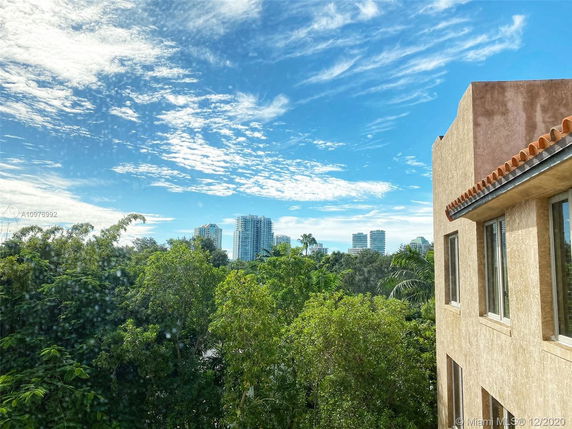 Building exterior with surrounding greenery and distant view of high-rise buildings